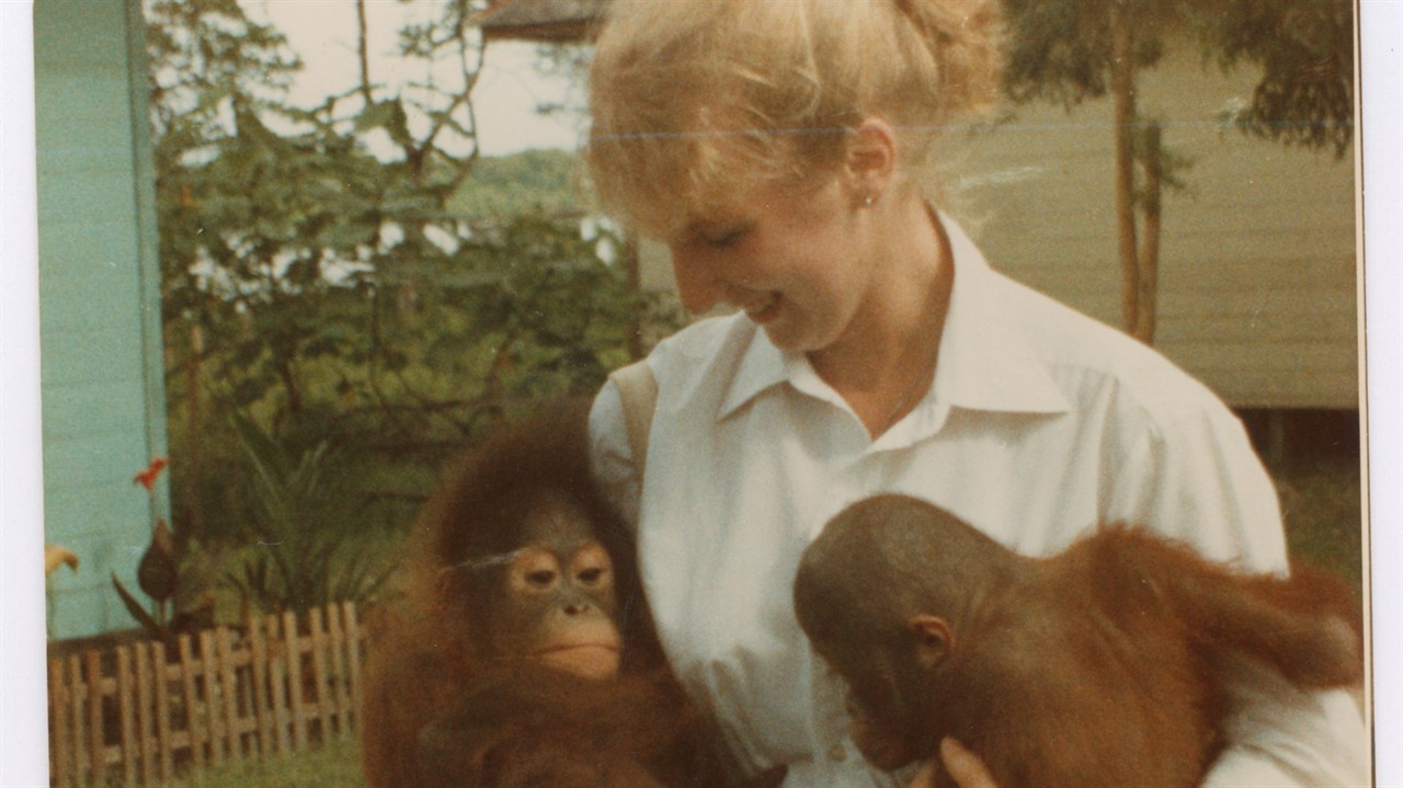 A woman holding two monkeys